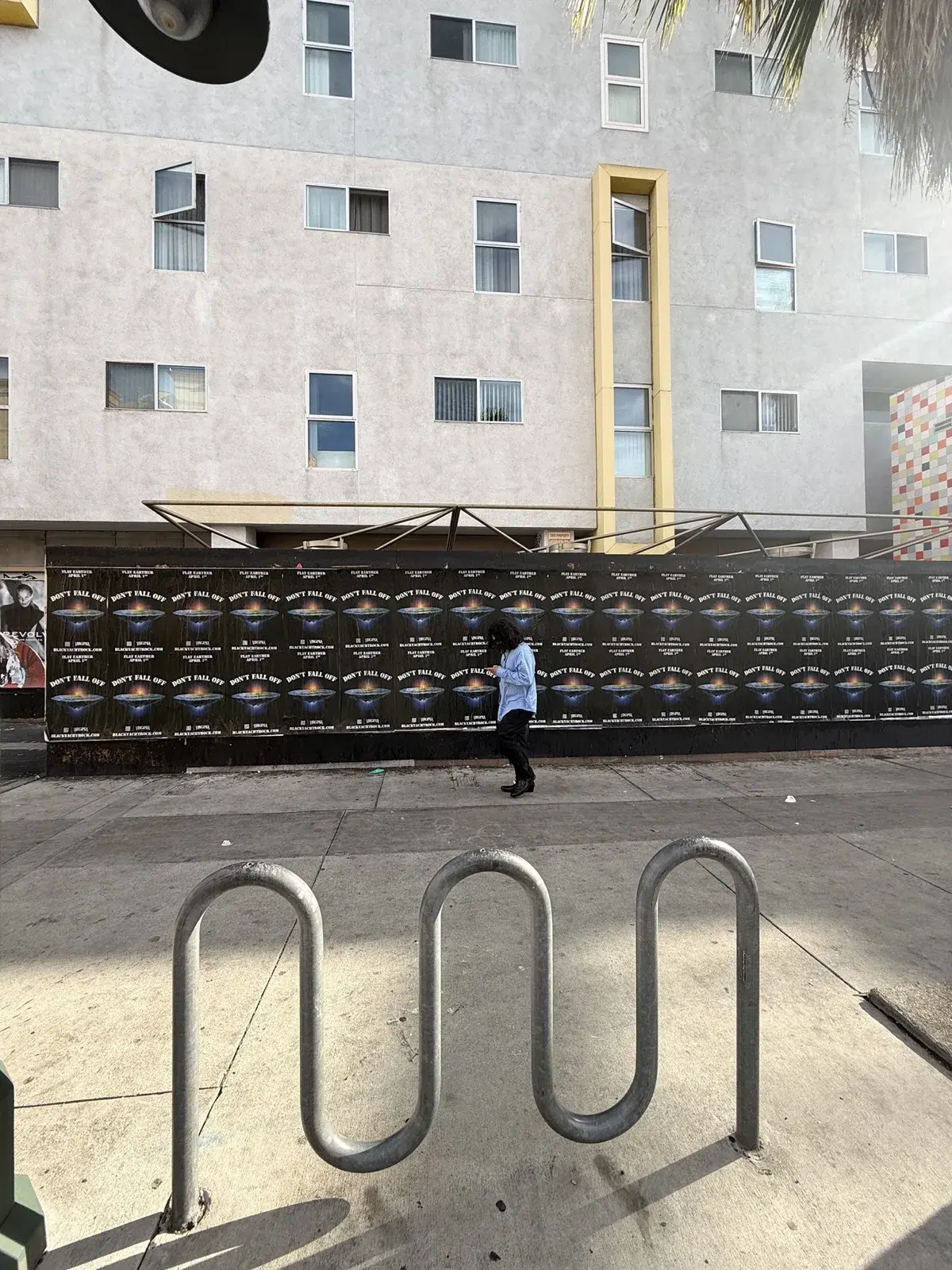 Don't Fall Off wheat paste campaign building wall installation street perspective with bike rack